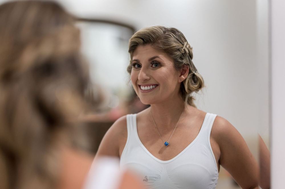 Mujer sonriendo frente al espejo durante los preparativos