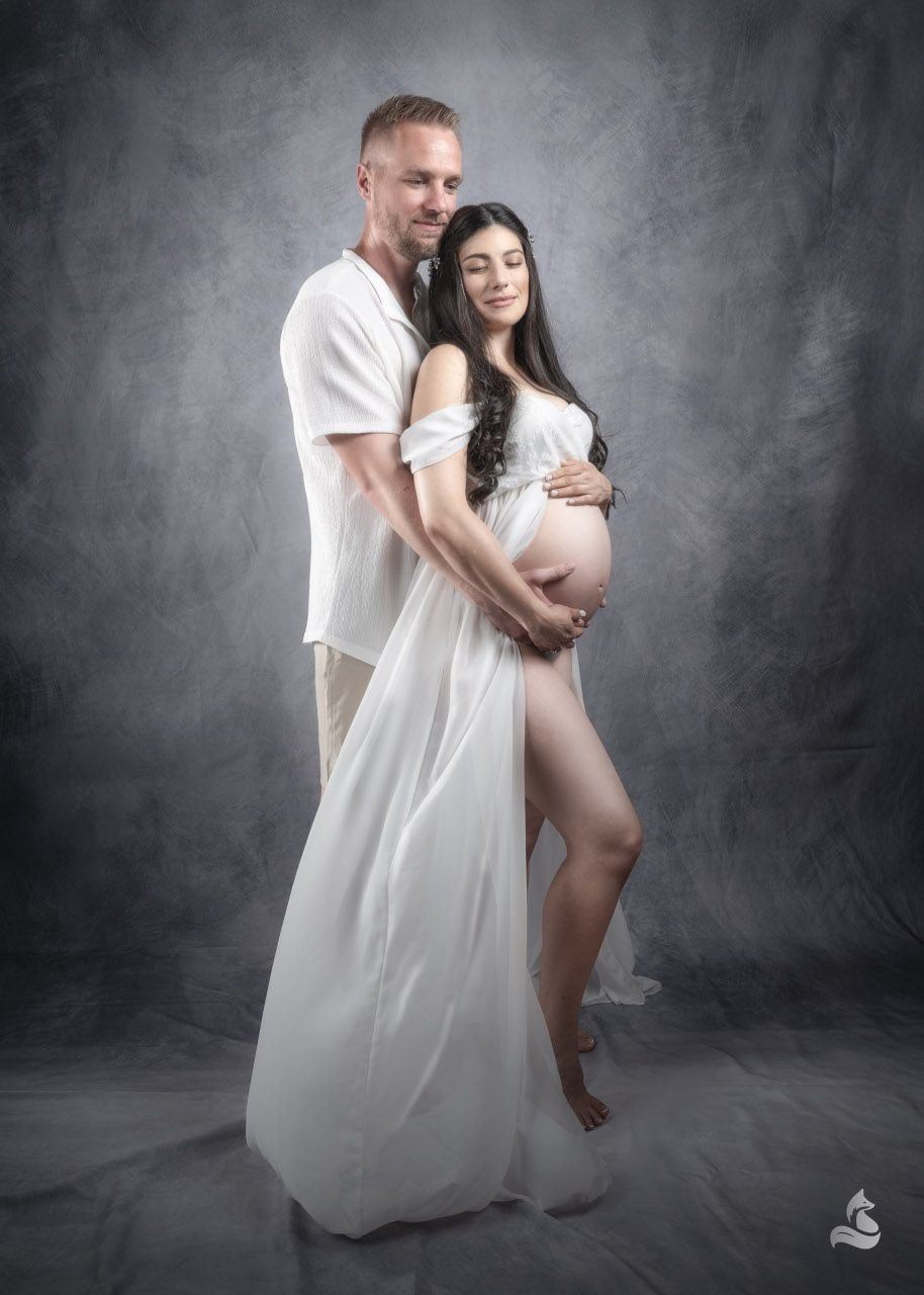 Pareja en sesión de maternidad sobre fondo gris